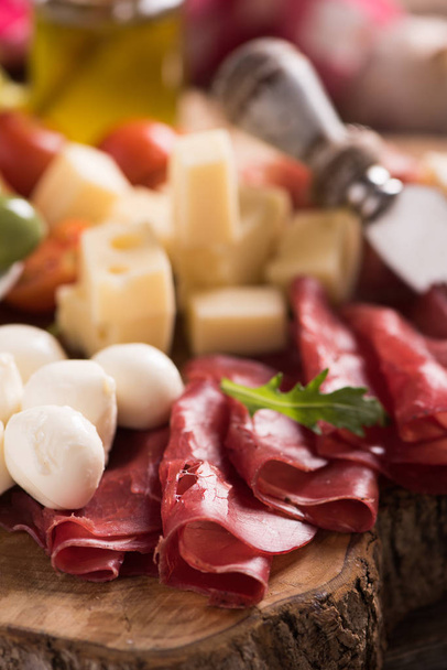 Assorted deli meats and a plate of cheese, on a wooden cutting b - Photo, Image