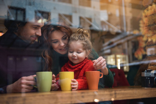 Happy father and mother with daughter in cafe - Фото, изображение