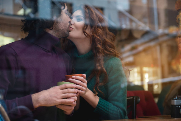 Happy married couple enjoying kiss in cafe - Zdjęcie, obraz