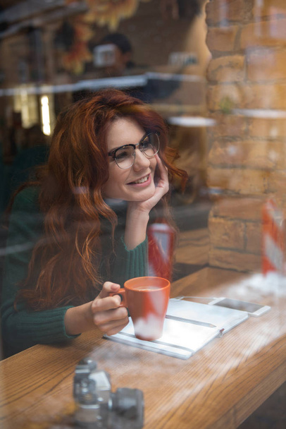 Menina bonita vendo rua enquanto sentado na cafetaria
 - Foto, Imagem