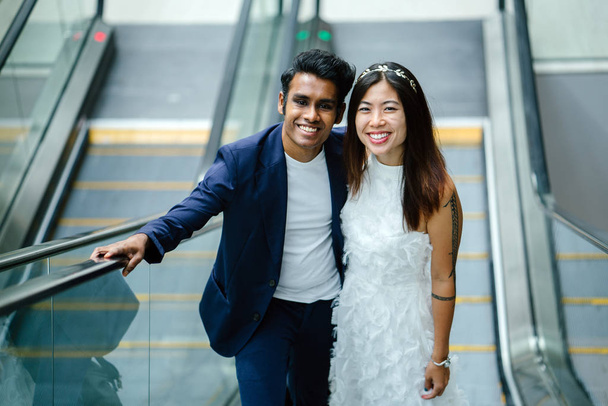  portrait of a young interracial couple getting married. An Indian man and his Chinese wife pose for a photograph in the day  - Foto, Imagen