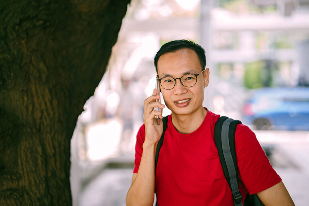 middle-aged Asian man with phone in city - Foto, afbeelding
