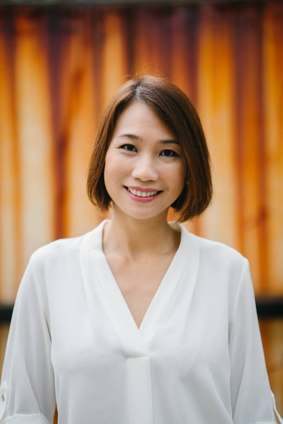 Portrait d'une gérante chinoise asiatique debout dans la journée. Elle se tient dans un couloir dans la journée et sourit avec confiance
. - Photo, image