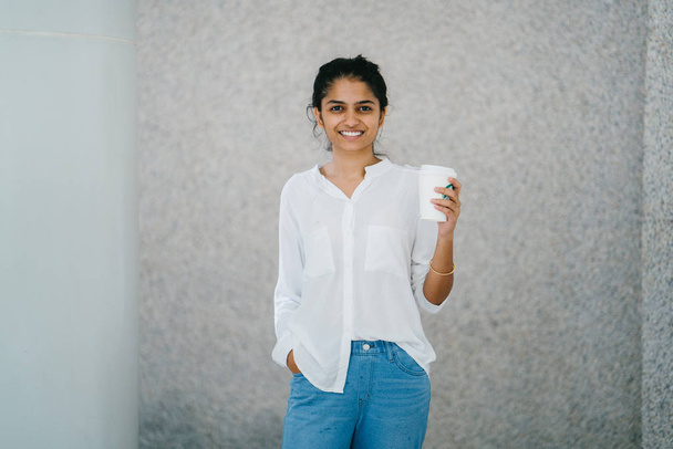 attraktive junge indische asiatische Frau lächelt mit einer Tasse Kaffee  - Foto, Bild