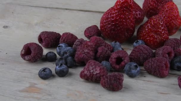 Fruta sana mezclada e ingredientes con fresa, frambuesa, arándanos. Bayas sobre fondo rústico de madera blanca
 - Metraje, vídeo