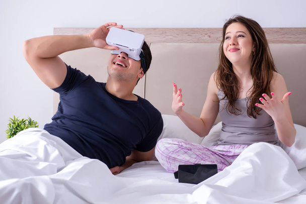 Femme et mari avec des lunettes de réalité virtuelle dans le lit - Photo, image