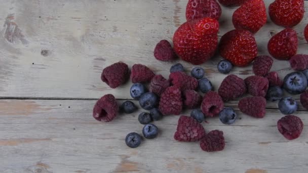Healthy mixed fruit and ingredients with strawberry, raspberry, blueberry. Berries on rustic white wooden background - Footage, Video