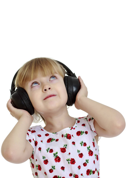 A little girl with headphones listening to music. - Foto, Bild
