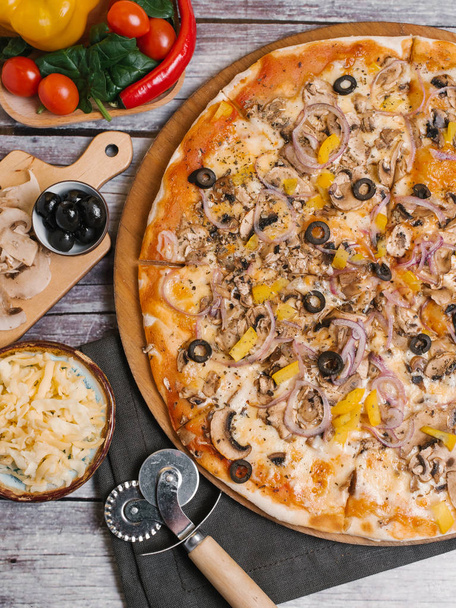 Pizza Paradicsom szósz, olajbogyó, édes hagyma, sárga paprika és a gomba szolgálják fel, a lemez fa pizza pizza vágó, szalvéta és veggies, fa deszka háttér - Fotó, kép