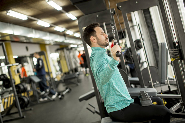 Handsome man doing excersise on a lat machine in gym - Foto, Imagem