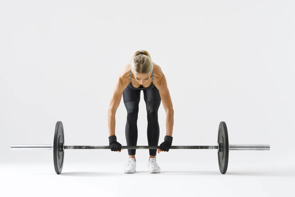 Fit young woman lifting barbell - Foto, afbeelding