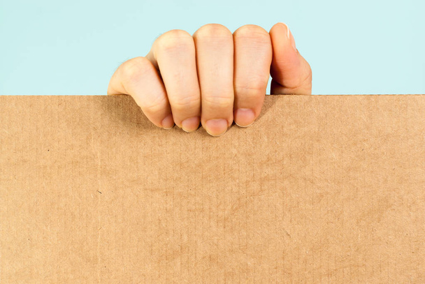 Mano mostrando un mensaje de cartón en blanco sobre fondo azul
 - Foto, Imagen