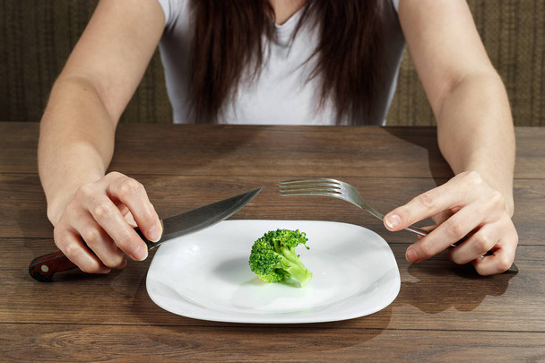 Photo of the fork with white plate and broccoli on wood table. The concept of a healthy diet, detox, weight loss, diet, eating problems, anorexia, bulimia. - Фото, изображение