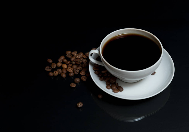kávé öntenek egy fehér kupa egy fekete felület asztalon szétszórt Pörkölt babkávé - Fotó, kép