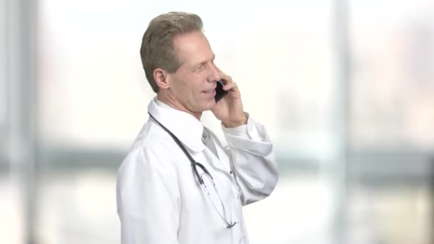 Cheerful doctor talking on phone, side view. - Video, Çekim
