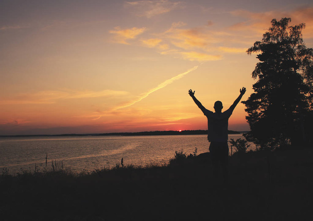 Momentos emocionales. Persona levantando brazos al amanecer / atardecer con hermosos colores y ambiente marino. Tema de vacaciones
. - Foto, Imagen