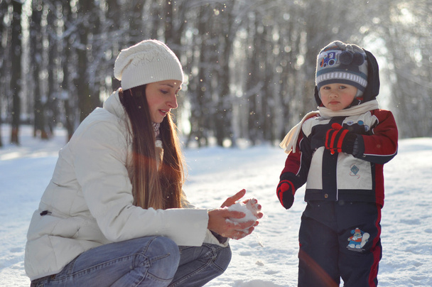 Nuori äiti tekee lumipalloja lapselle talvella kävellä
 - Valokuva, kuva
