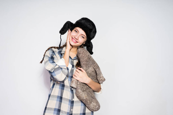 happy beautiful russian girl in fur hat holds warm winter felt boots - Photo, image