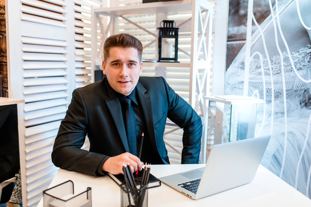 Businessman working at laptop in beautiful office and smiling.. - Foto, Bild
