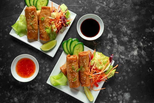 Chinese vegetable spring rolls garnished with fresh salad, lime wedges, sweet chilli sauce and soy sauce - Photo, Image
