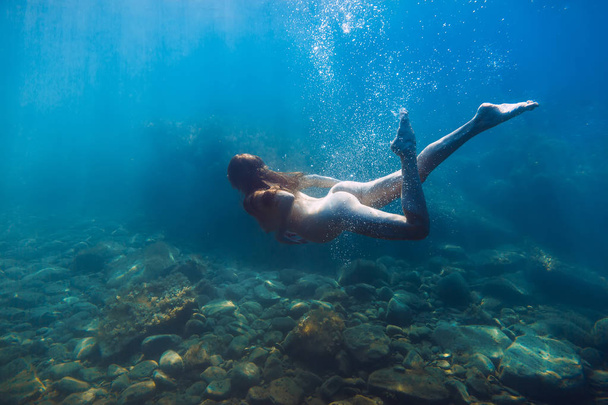 Mujer embarazada joven está bajo el agua en el océano azul
 - Foto, Imagen