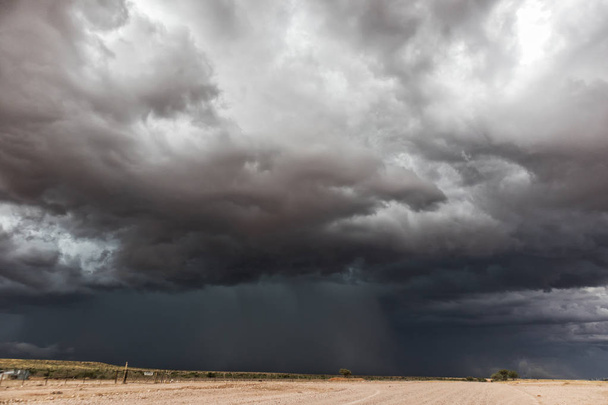 Гравийная дорога на пути в пустыню Намибии с чрезвычайно драматическим небом, бурей
. - Фото, изображение