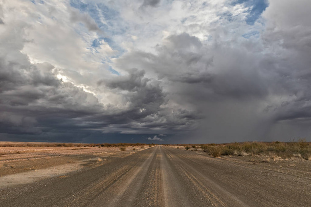 Гравийная дорога со штормовым небом, на пути в пустыню Намибия. Соссувлеи
. - Фото, изображение