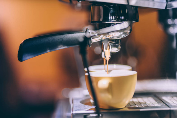 Detalhes da máquina de café expresso derramando e preparando café fresco e cremoso no bistrô, restaurante ou pub local
 - Foto, Imagem