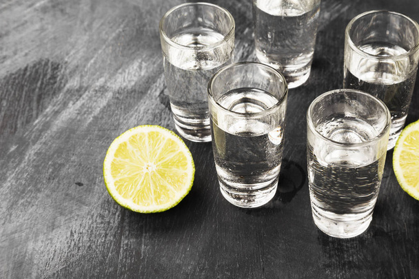 Cold vodka in shot glasses on a black background - Фото, изображение