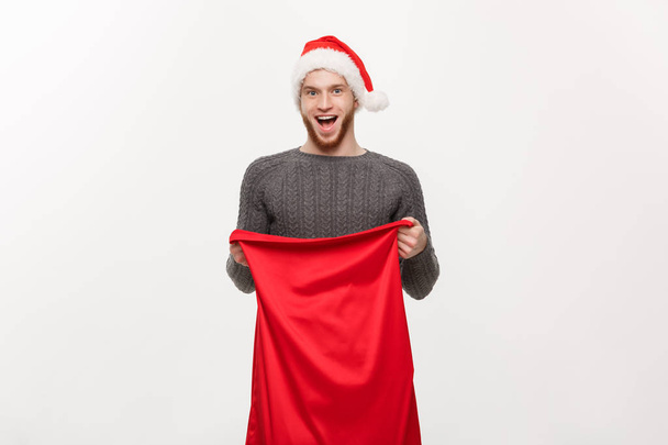 Christmas concept - Young beard handsome man exciting open santa big bag for present. - Foto, afbeelding