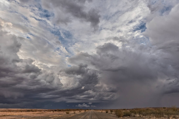 Гравийная дорога со штормовым небом, на пути в пустыню Намибия. Соссувлеи
. - Фото, изображение