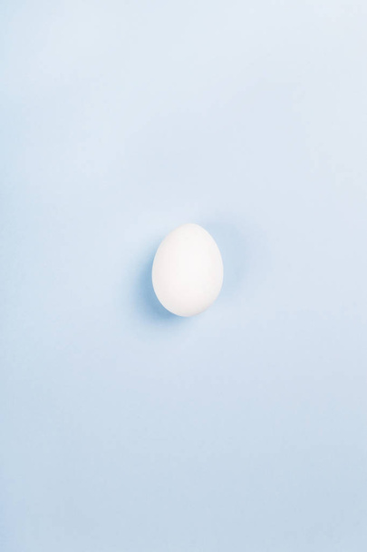 White egg on blue background. Top view - Zdjęcie, obraz