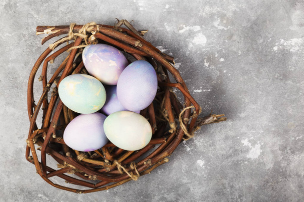 Multi-colored eggs for Easter in nest on gray background. Top vi - Photo, Image