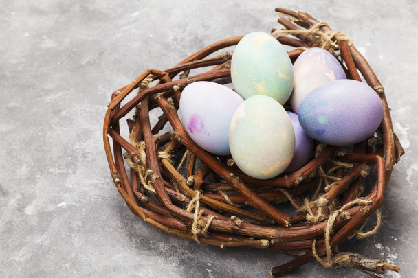 Multi-colored eggs for Easter in nest on gray background. Copy s - Foto, Bild