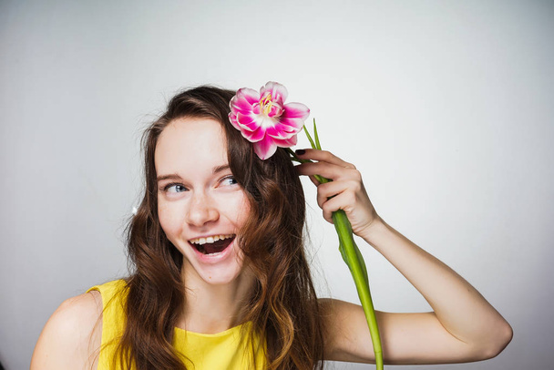 happy laughing girl in yellow dress holds a flower, celebrates Mother's Day - Фото, изображение