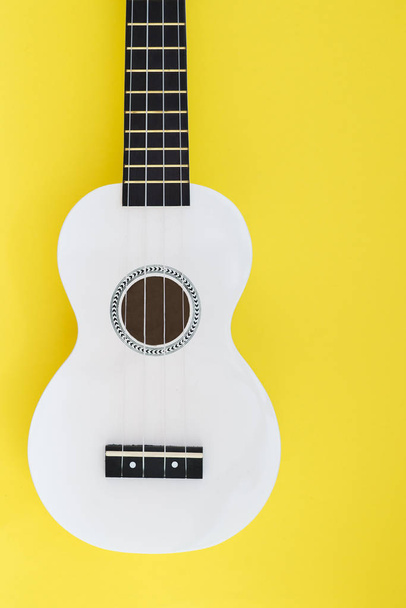 Biały ukulele na żółtym tle. Mieszkanie świeckich koncepcji muzycznych - Zdjęcie, obraz