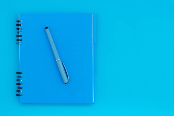 Μπλε σημειωματάριο με ένα μολύβι πάνω σε μπλε φόντο. Επίπεδη Lay πρότυπο. Θέση για το κείμενο - Φωτογραφία, εικόνα