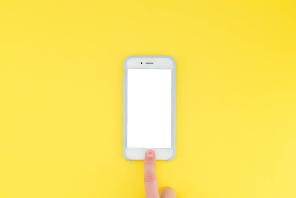 El dedo humano desbloquea el teléfono inteligente sobre un fondo amarillo. Puesta plana
 - Foto, imagen