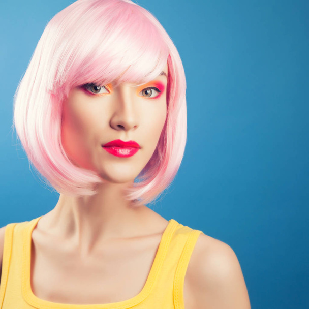 beautiful woman wearing pink wig against blue background - Фото, изображение