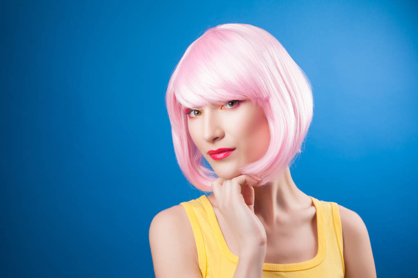 beautiful woman wearing pink wig against blue background - Foto, imagen