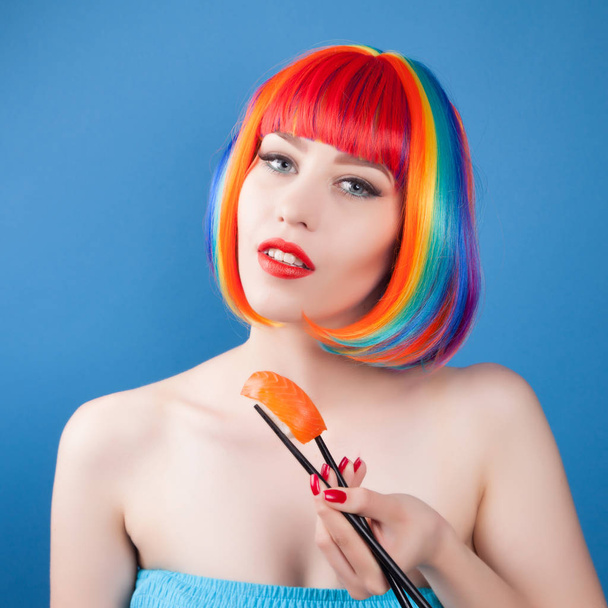 Beautiful girl with red lips and color hair eating sushi close-up - Fotó, kép