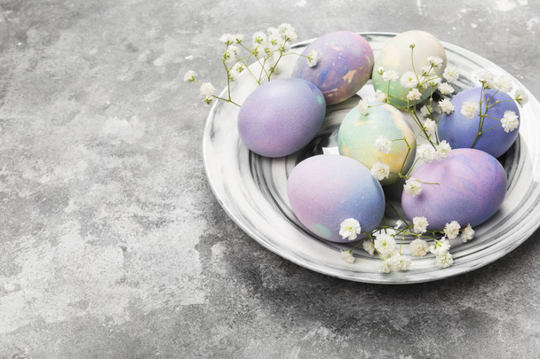 Multicolored eggs for Easter in marble plate with white flowers  - Foto, Bild