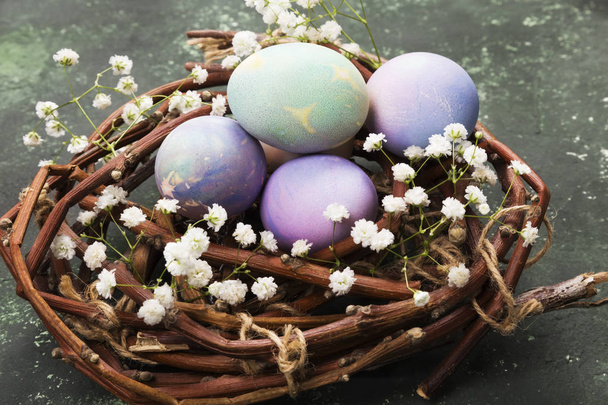 Multicolored eggs for Easter in nest with flowers on green backg - Photo, Image