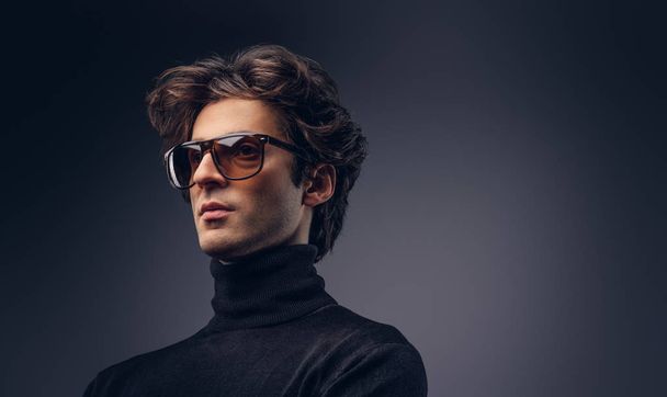 Studioporträt eines sinnlichen Machos mit stylischem Haar im schwarzen Pullover und Sonnenbrille. - Foto, Bild