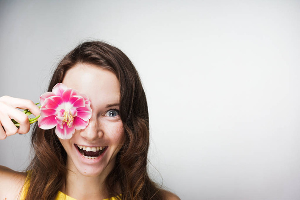 smiling happy young woman holding a fragrant pink flower, celebrating World Women's Day - Zdjęcie, obraz