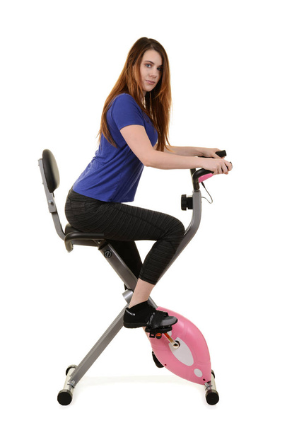 jovem mulher montando uma bicicleta de exercício
 - Foto, Imagem