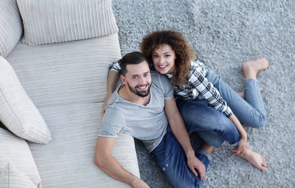 young couple sitting on the carpet in the new living room - Photo, image