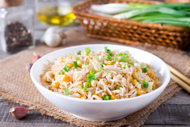 Schüssel mit gebratenem Reis, Mais und Ei auf einem hölzernen Hintergrund. gesund und leicht. - Foto, Bild