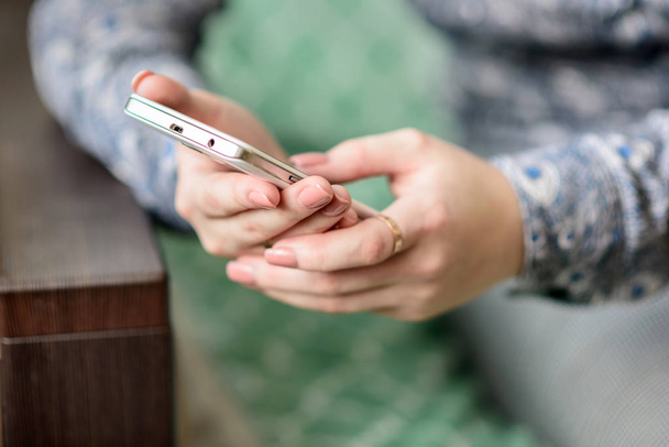 Primer plano de las manos femeninas sosteniendo un teléfono inteligente. Una mujer joven utiliza un teléfono inteligente para comunicarse en Internet
. - Foto, imagen