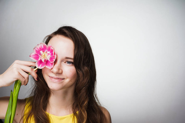 beautiful blue-eyed girl holding a fragrant pink flower, celebrating the world women's day - Foto, afbeelding